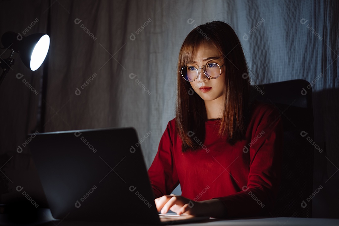 Mulher asiática trabalhando tarde da noite com laptop em casa