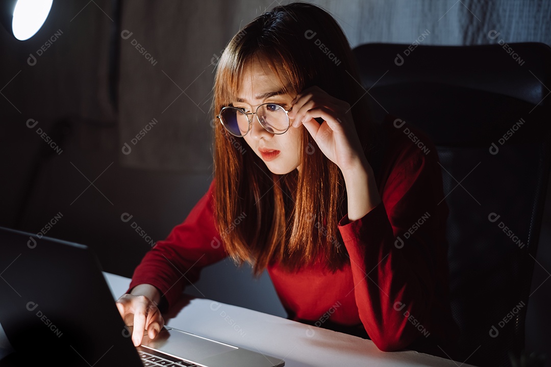 Mulher asiática trabalhando tarde da noite com laptop em casa