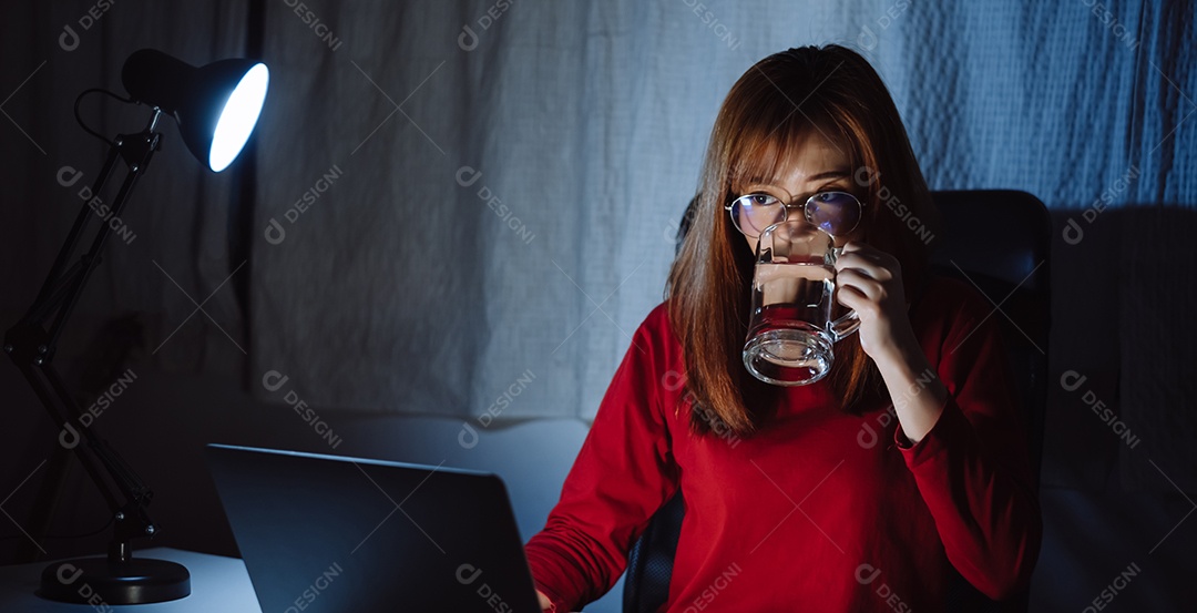 Mulher asiática trabalhando tarde da noite com laptop em casa