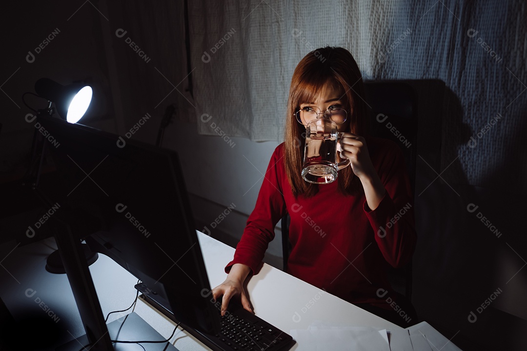 Mulher asiática trabalhando tarde da noite com laptop em casa