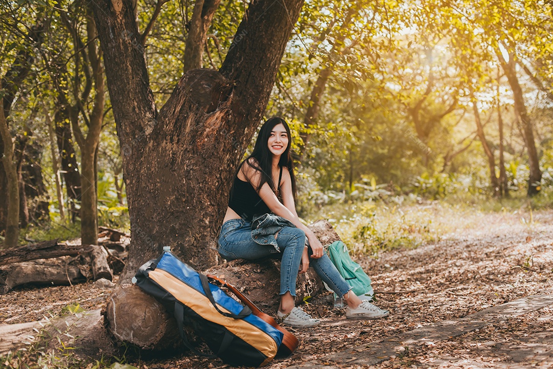 Retrato de uma mulher asiática com seu sorriso caminhando na floresta acampando