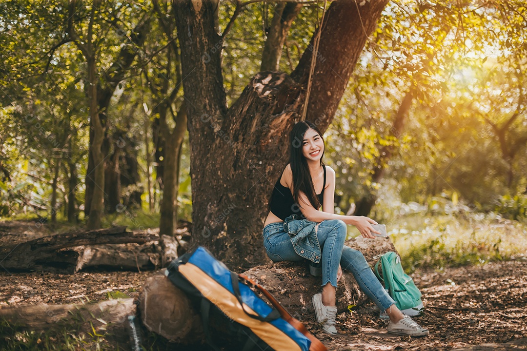 Retrato de uma mulher asiática com seu sorriso caminhando na floresta acampando