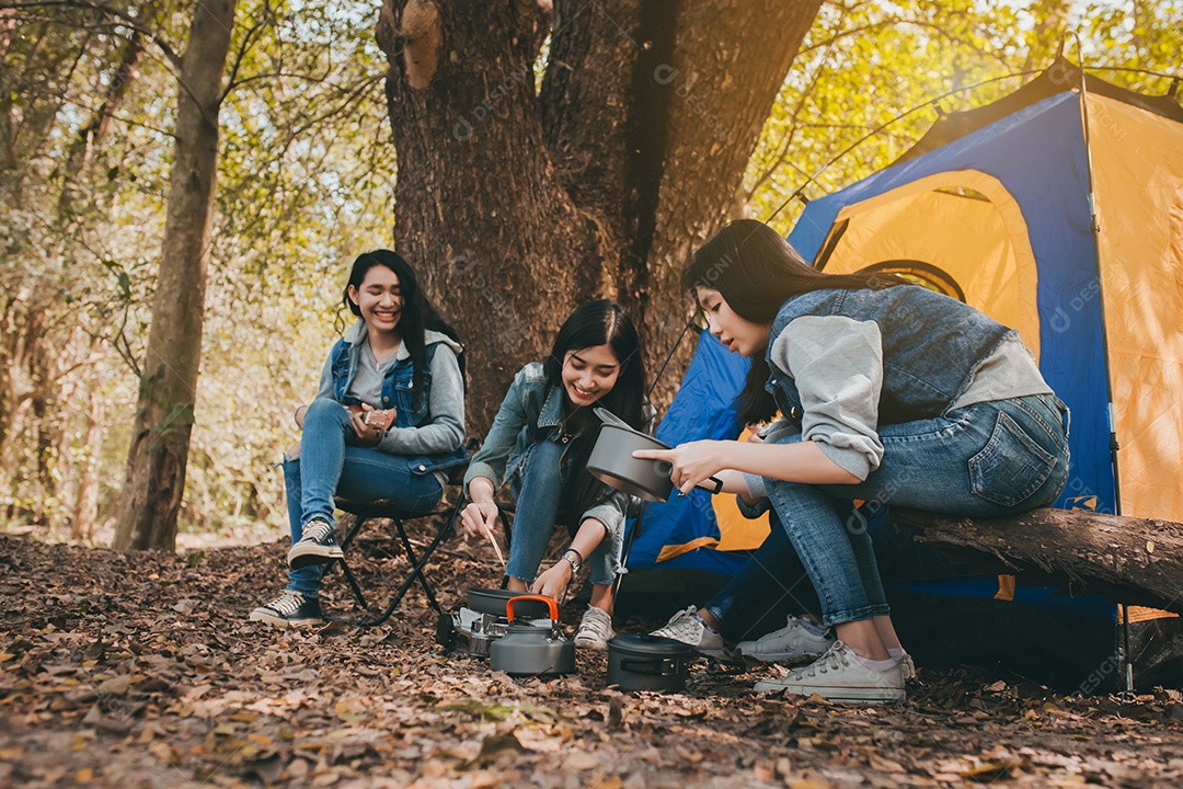 Grupo de jovens mulheres asiáticas acampando e descansando na floresta tocando ukulele