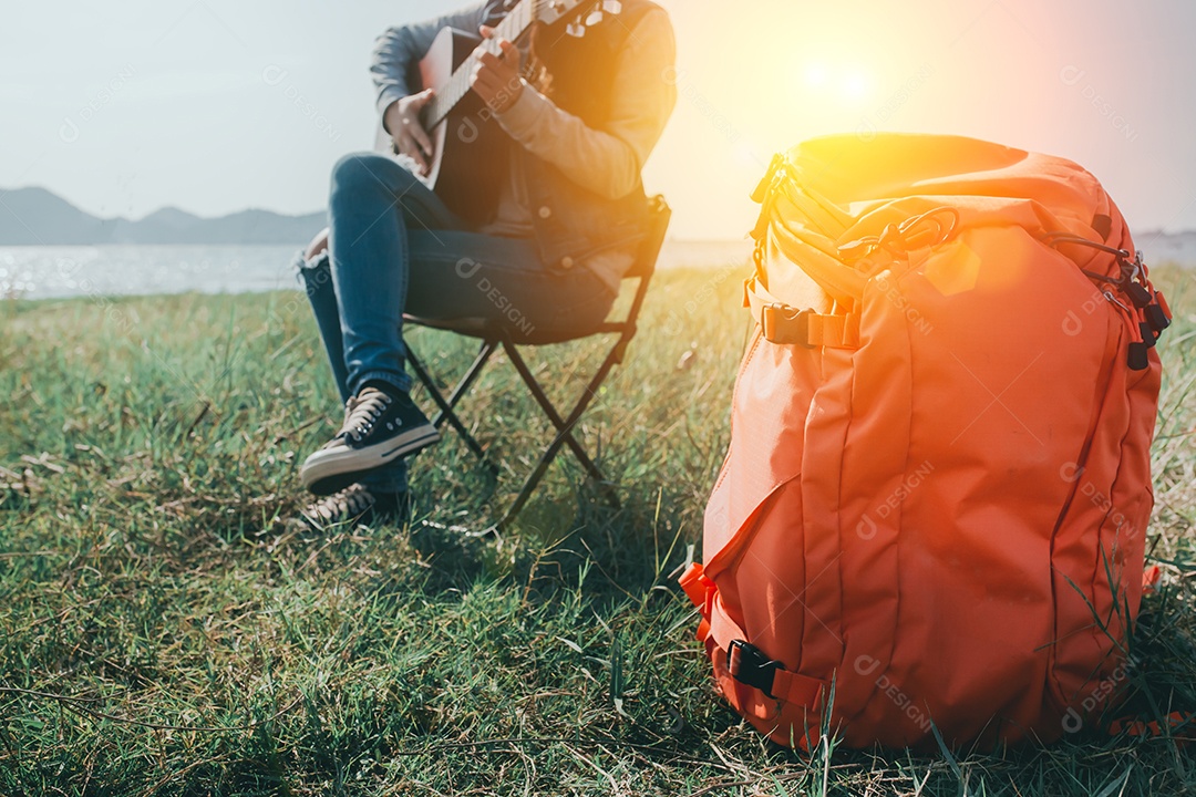 Mochila de mulher tocando violão descansando ao ar livre