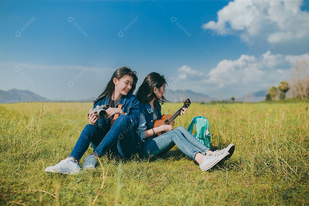 Amizade de mulheres adolescentes asiáticas descansando ao ar livre com câmera e ukulele que ela toca música relaxa.