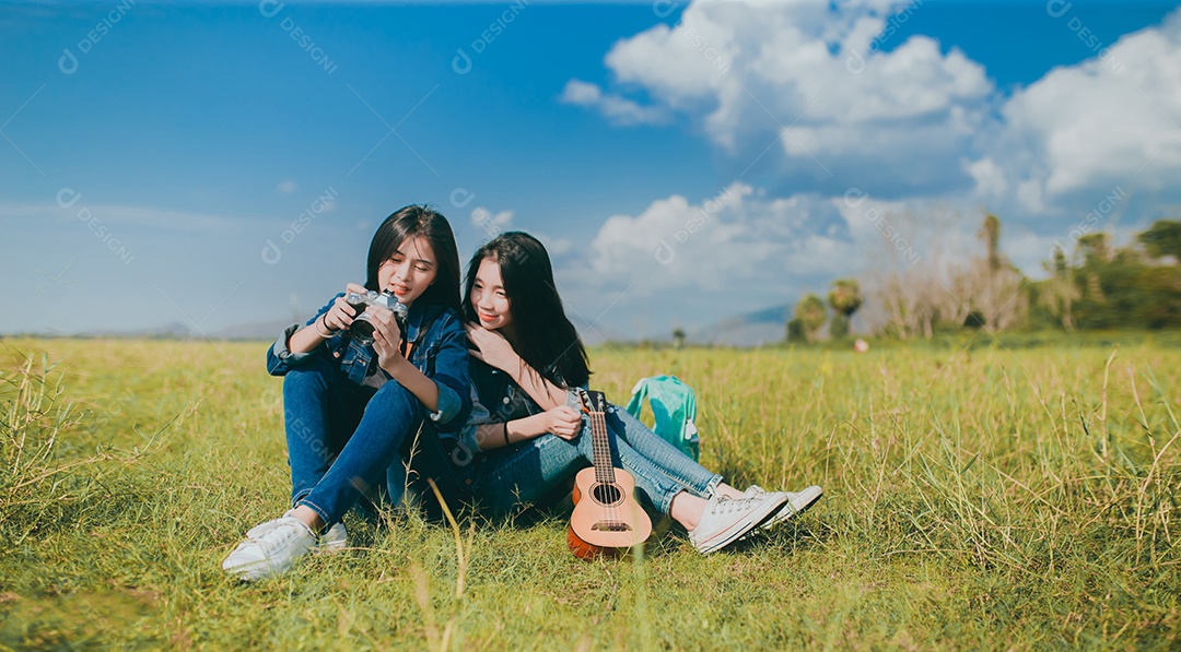 Amizade de mulheres adolescentes asiáticas descansando ao ar livre com câmera e ukulele que ela toca música relaxa.