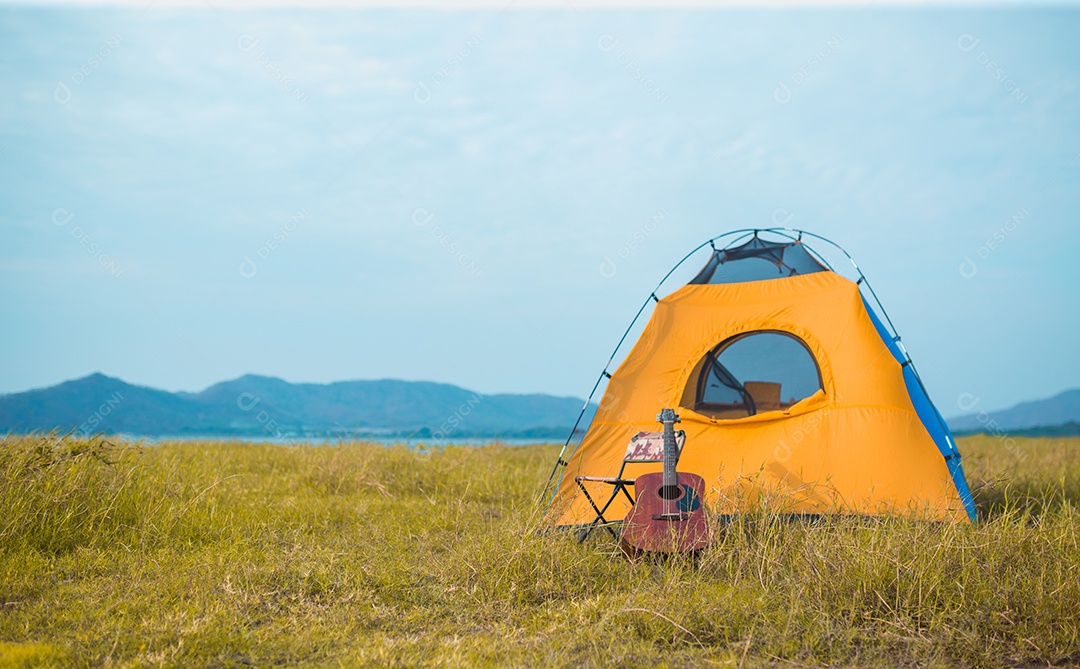 Barraca de acampamento, cadeira e guitarra perto da montanha do rio na floresta para viagens.