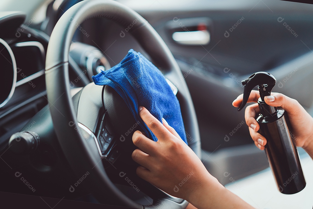 Mãos profissionais de mulher limpando volante e console de carro