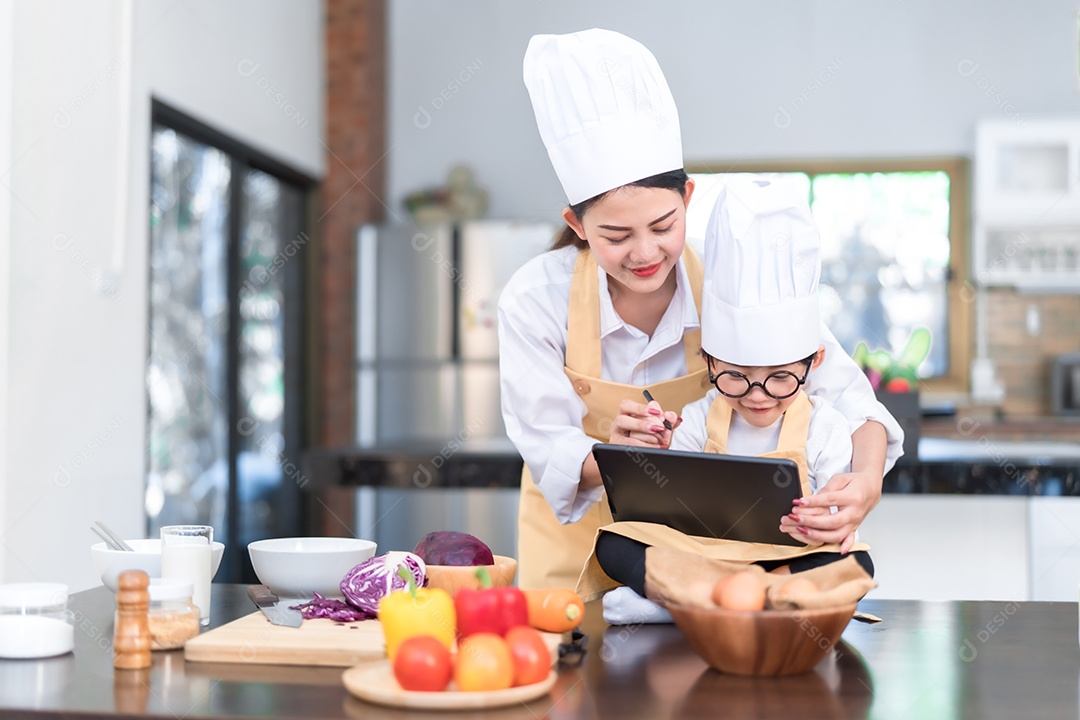 Chef profissional mãe asiática ensinando menu de lista de filho pequeno cozinhando vegetais