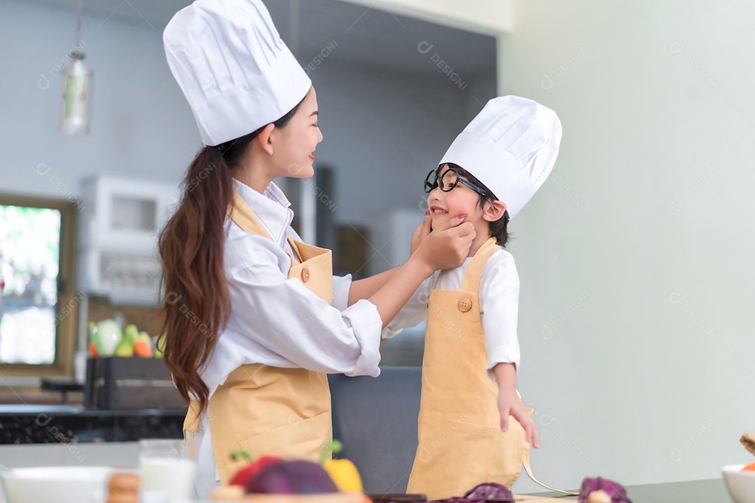 Mãe asiática de família feliz abraçando filho pequeno cozinhando