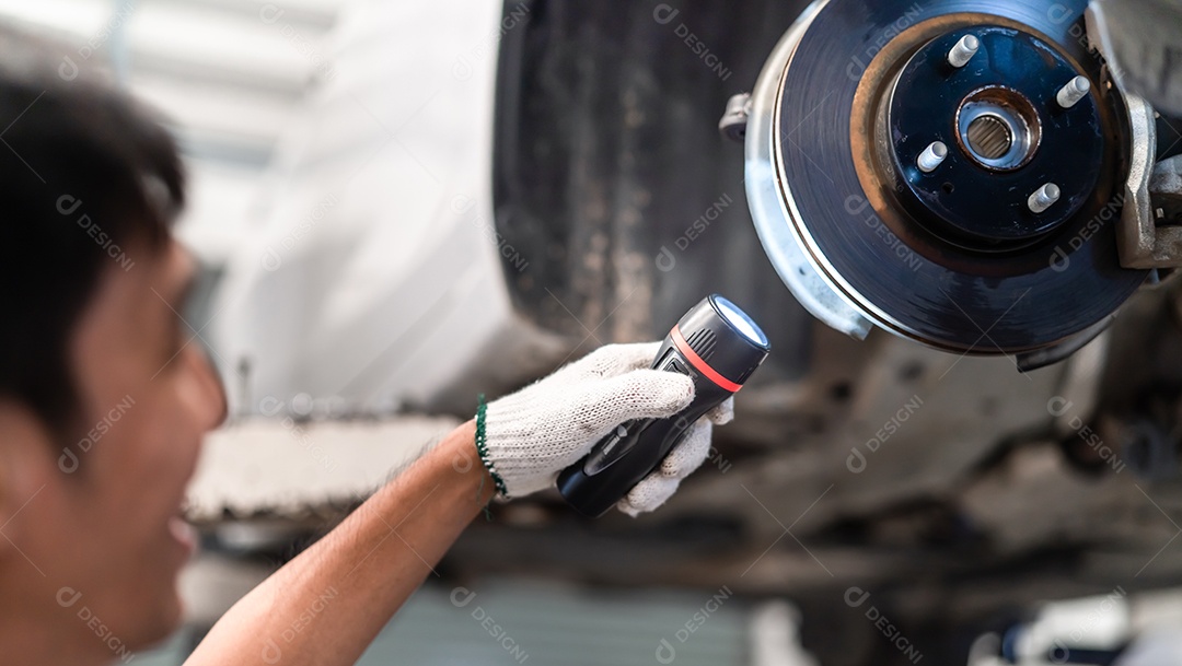 Homem asiático mecânico examinando e manutenção de serviço a suspensão de um veículo