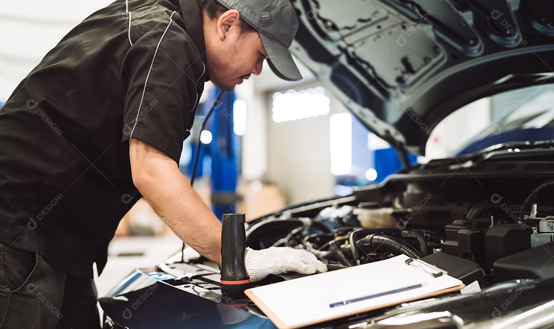 Homem asiático mecânico examinando o carro