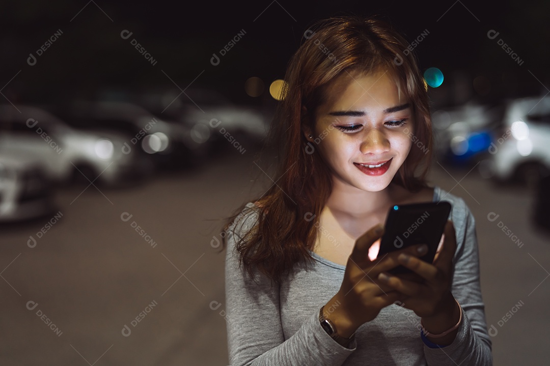 Mulher de beleza olhando smartphone celular à noite na rua