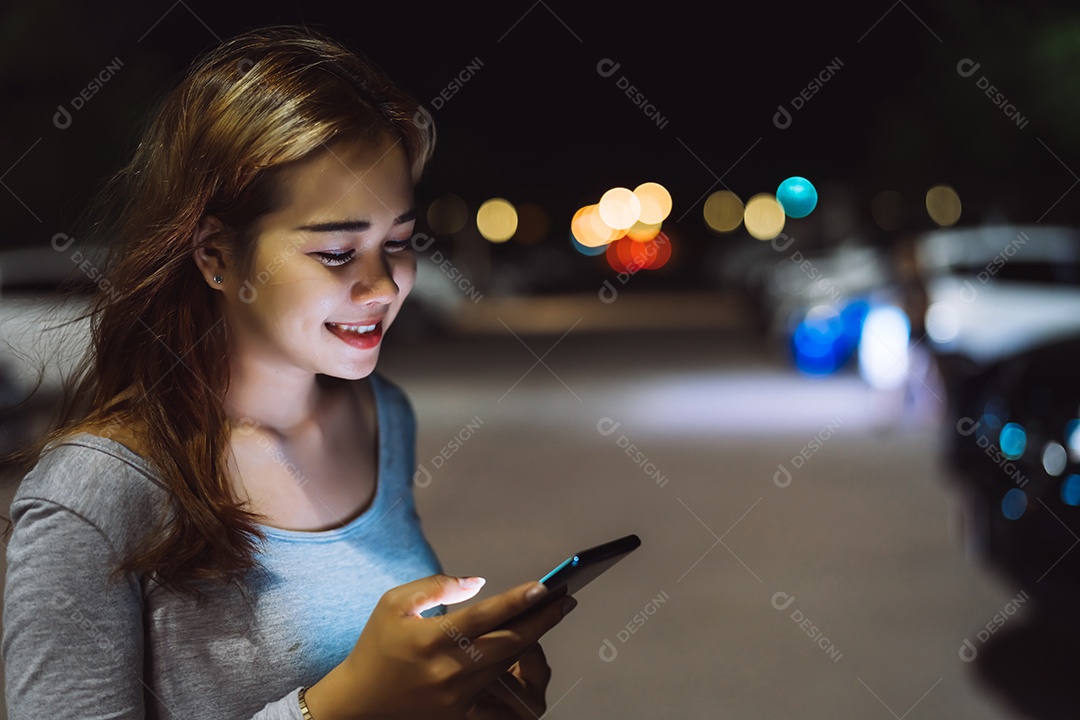 Mulher de beleza olhando smartphone celular à noite na rua
