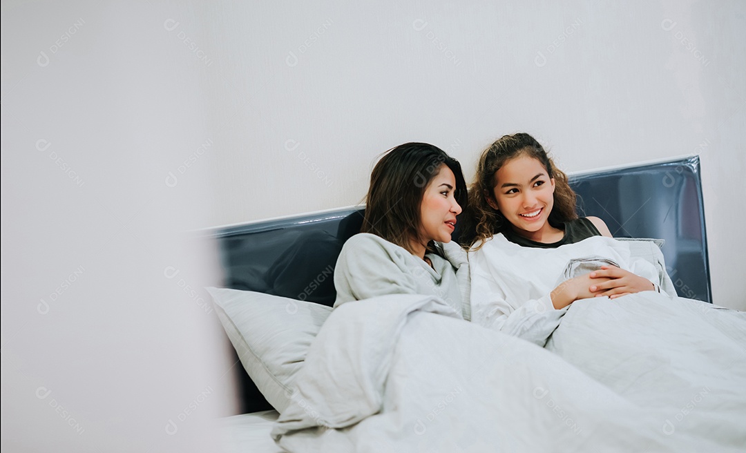 Filha adolescente beijando Mãe Família feliz deitada na cama