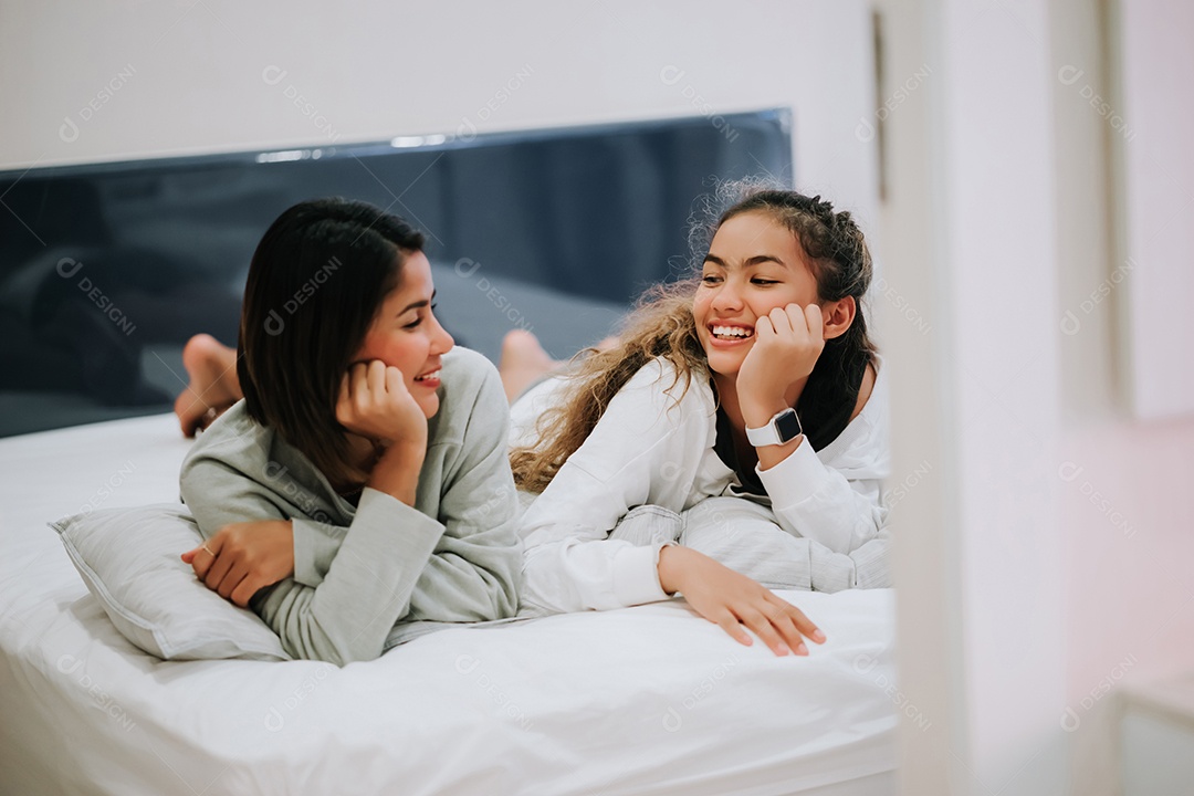 Filha adolescente beijando Mãe Família feliz deitada na cama