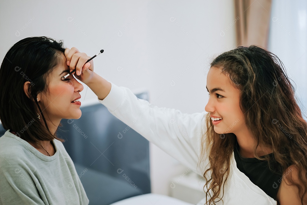 A filha adolescente maquiando a mãe
