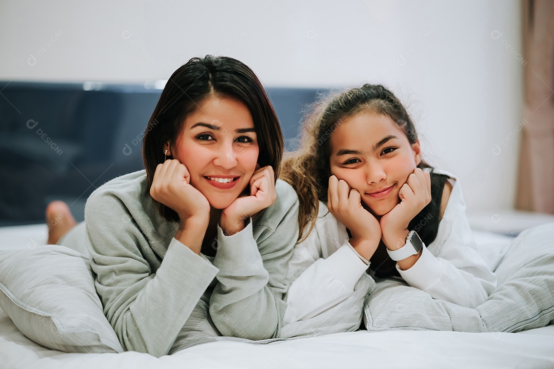 Filha adolescente beijando Mãe Família feliz deitada na cama