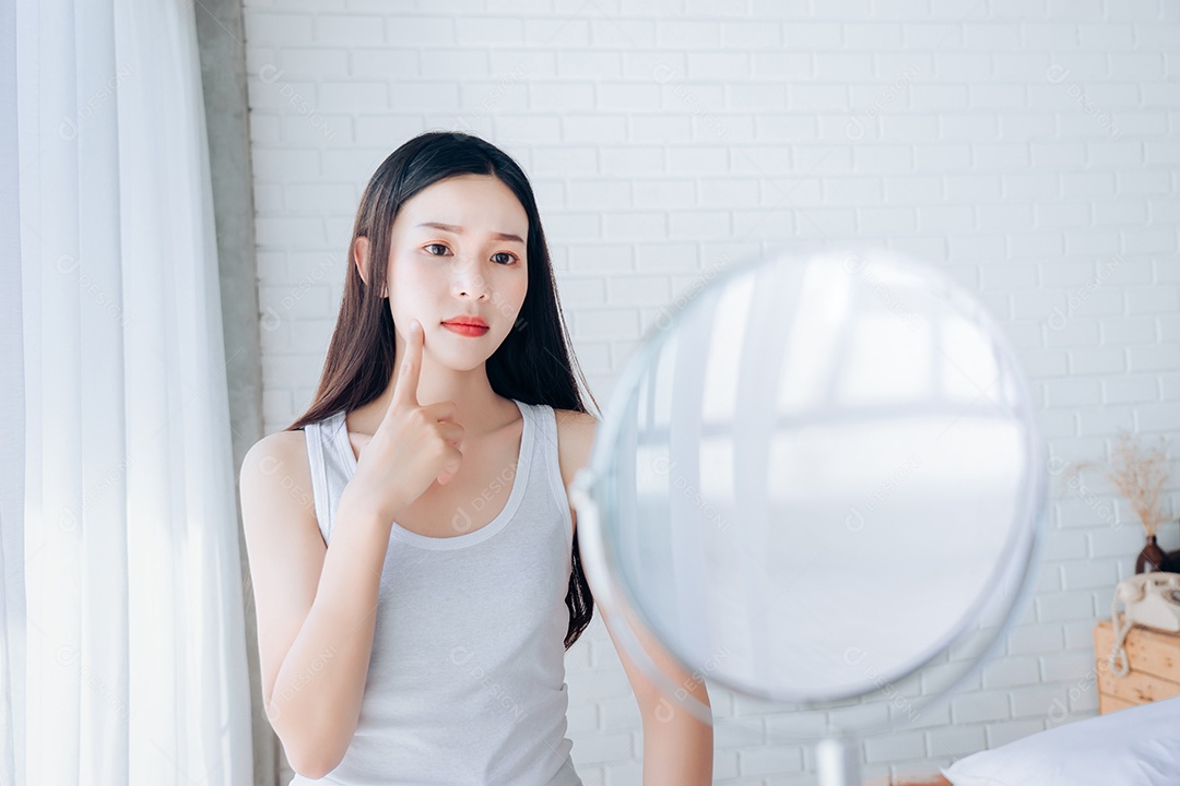 A jovem mulher asiática espreme acne no rosto