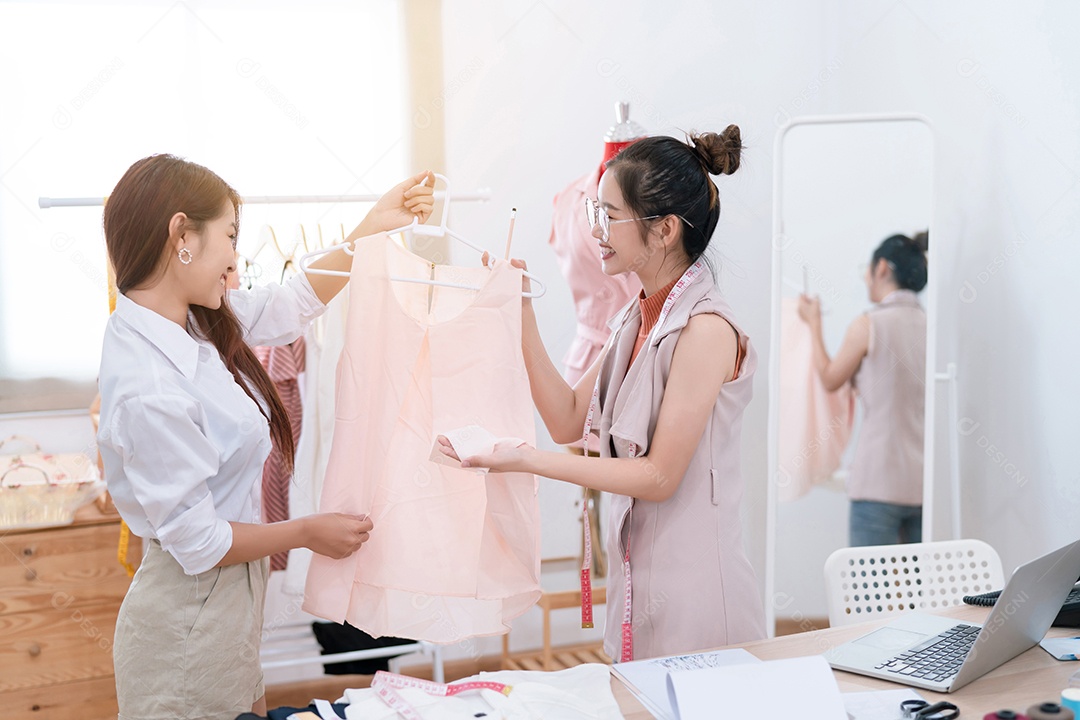 Linda estilista de moda asiática trabalhando e costurando suas roupas de serviço para o cliente