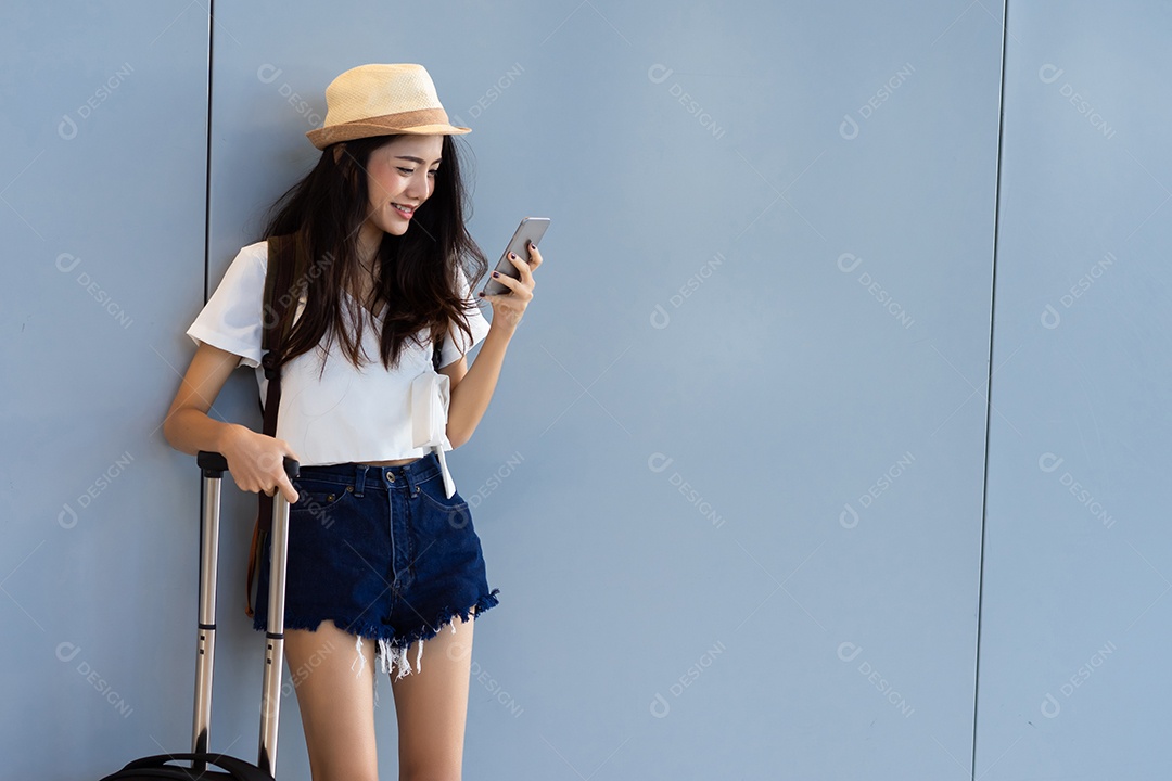 Adolescente asiática parada no terminal do aeroporto com mala de bagagem e mochila para viajar