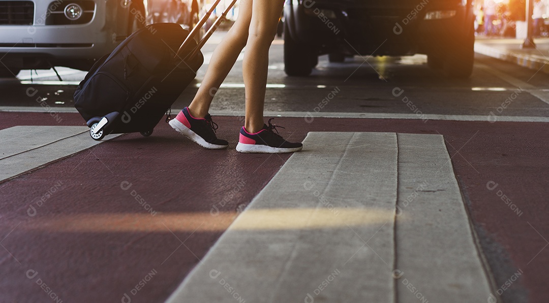 Pernas de mulher andando no aeroporto segurando mala para viajar