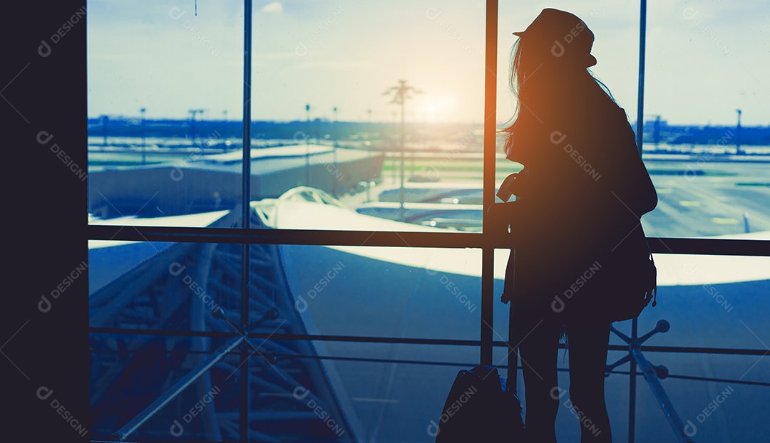 Silhueta mulher viaja com bagagem olhando janela no terminal do aeroporto