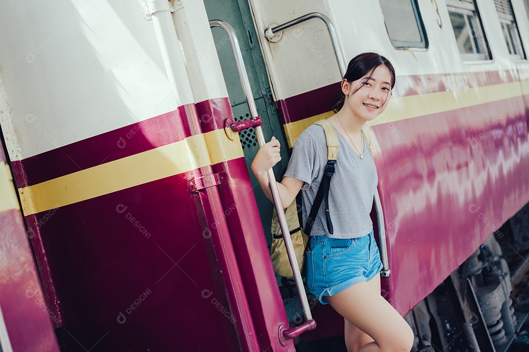 Jovem turista asiática pega o trem com mochila