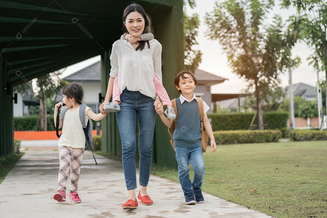Mãe e aluno e filhos de mãos dadas indo para a escola