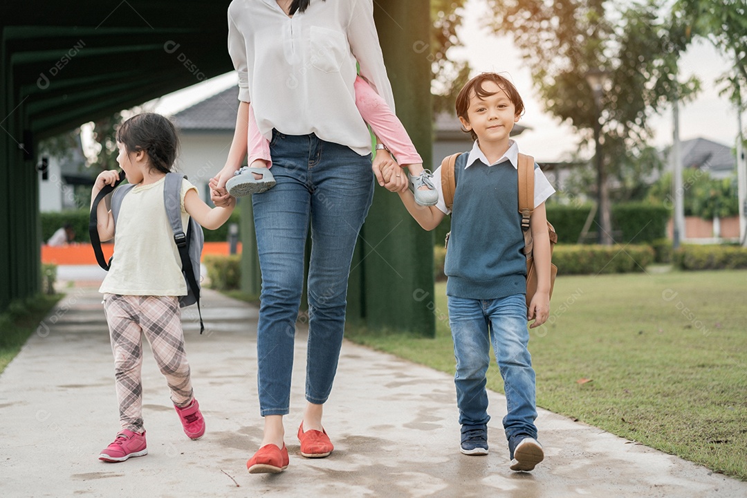 Mãe e aluno e filhos de mãos dadas indo para a escola