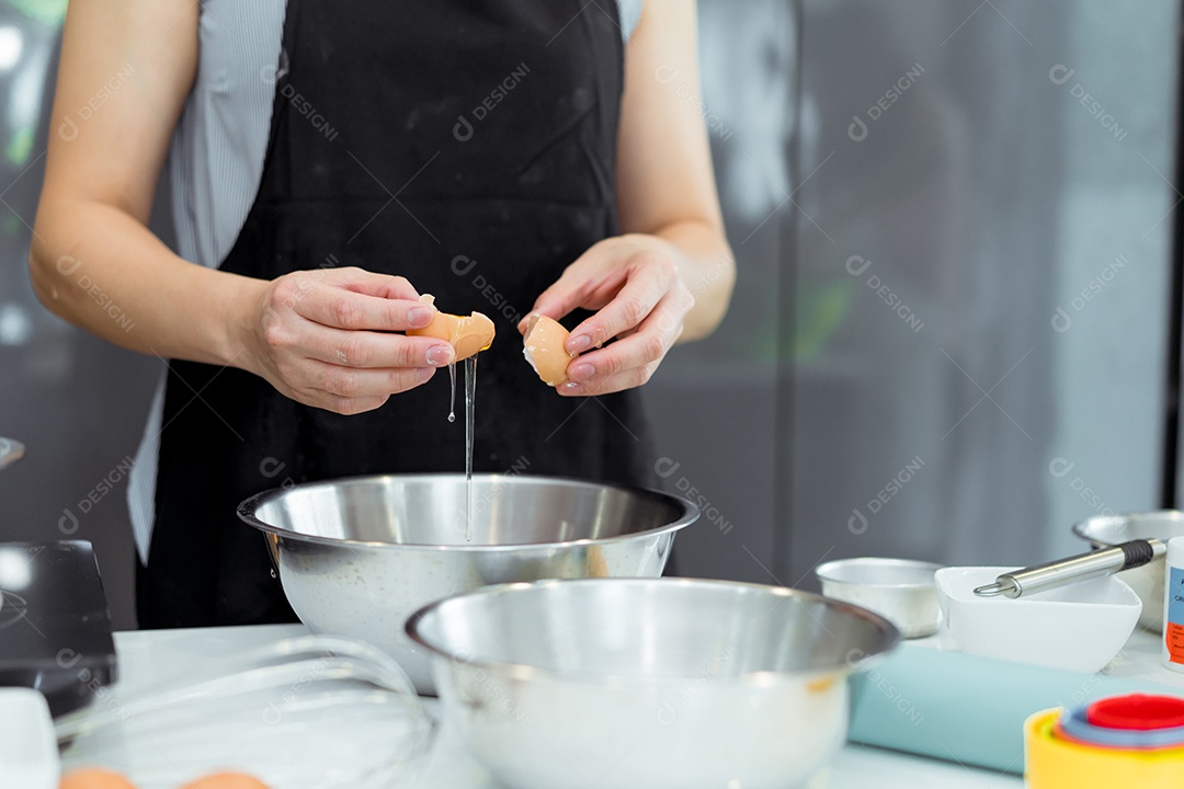 Mulher cozinhando na cozinha quebrando ovo na tigela