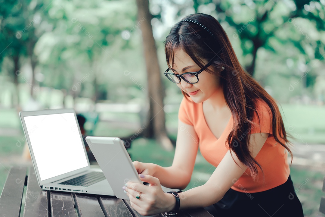 Menina usando tablet e laptop conceito on-line de marketing no parque ao ar livre