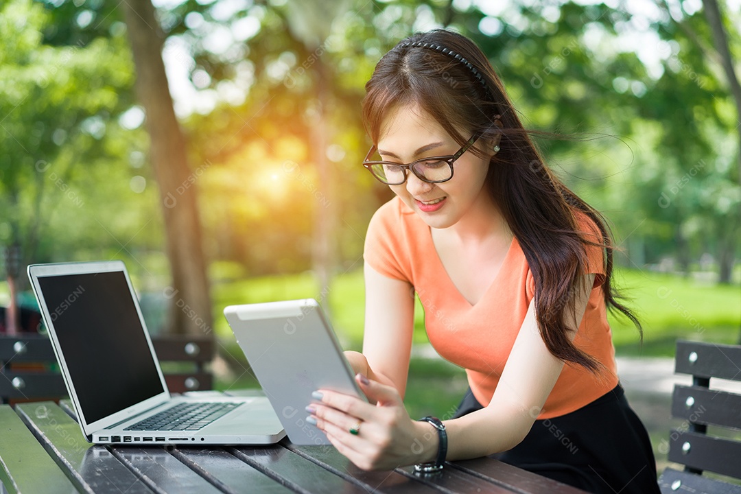 Menina usando tablet e laptop conceito on-line de marketing no parque ao ar livre