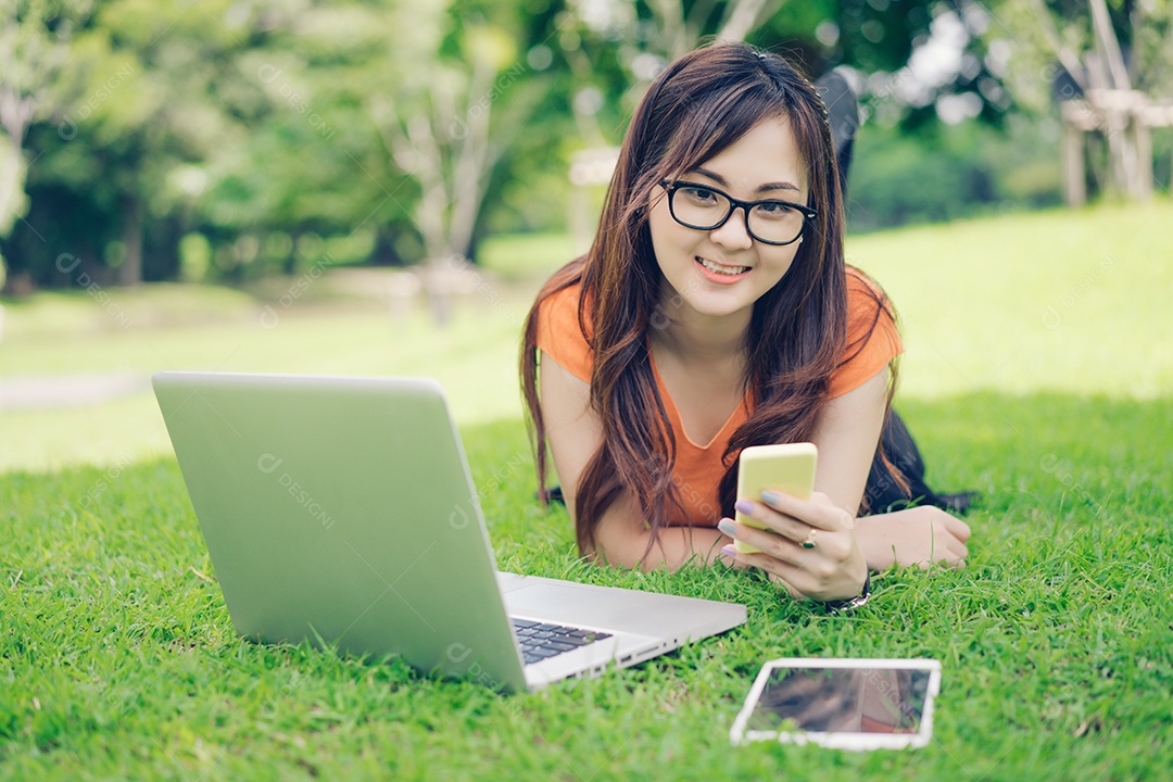 Menina usando smartphone, tablet e laptop conceito on-line de marketing no parque ao ar livre