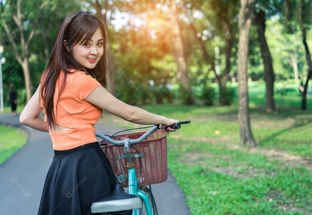 A moça com bicicleta relaxa e descansa o sorriso no parque ao ar livre