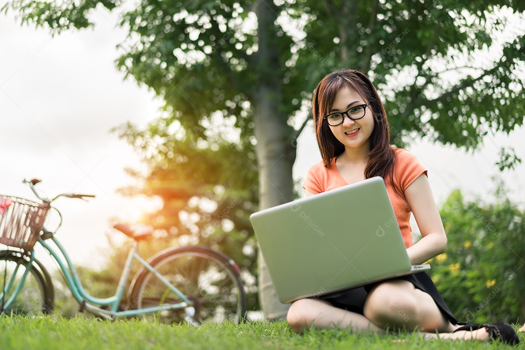 Menina usando notebook com bicicleta no parque