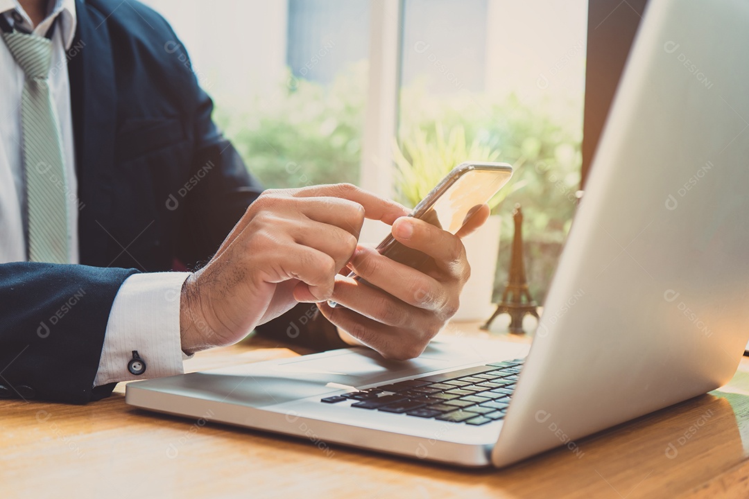 Empresário usando smartphone e laptop no local de trabalho