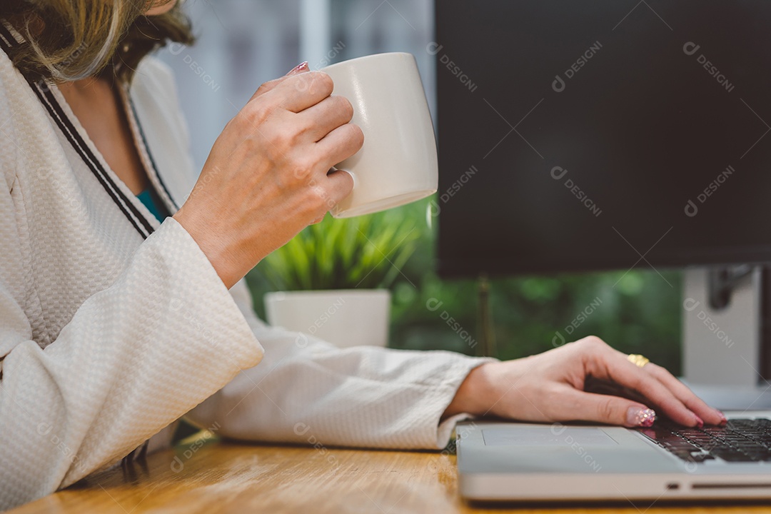 Empresária trabalhando com computador portátil e bebendo café na xícara