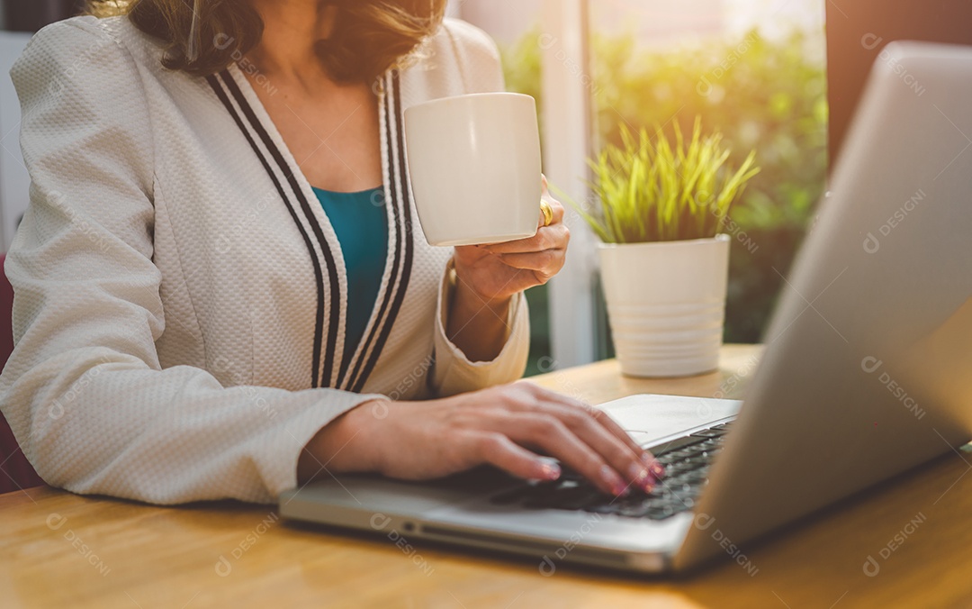 Empresária trabalhando com computador portátil e bebendo café na xícara
