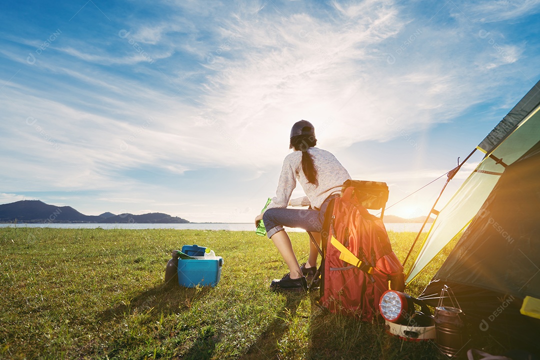 Mulher acampando sentada relaxa sozinha com bebidas