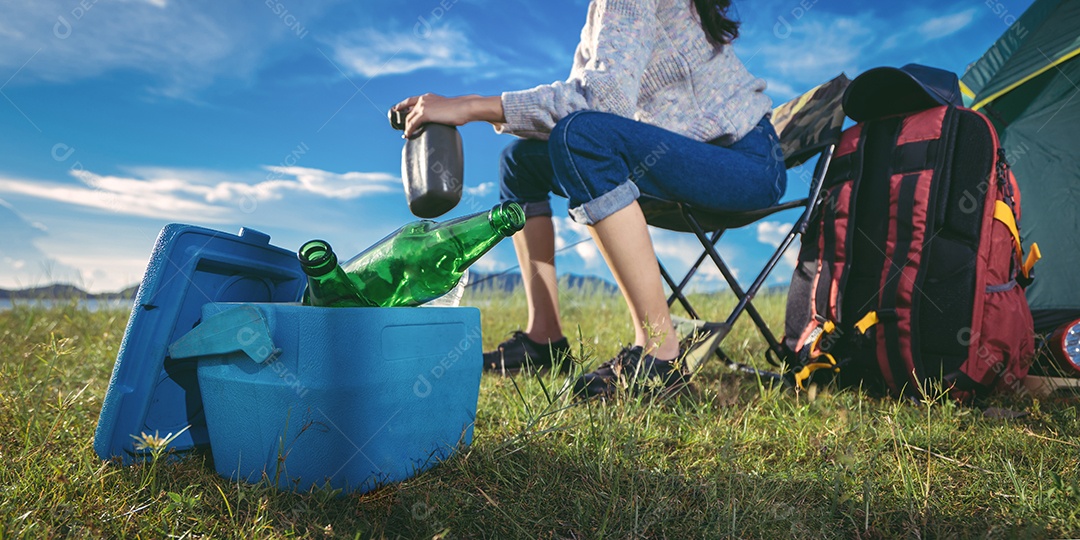 Mulher acampando sentada relaxa sozinha com bebidas