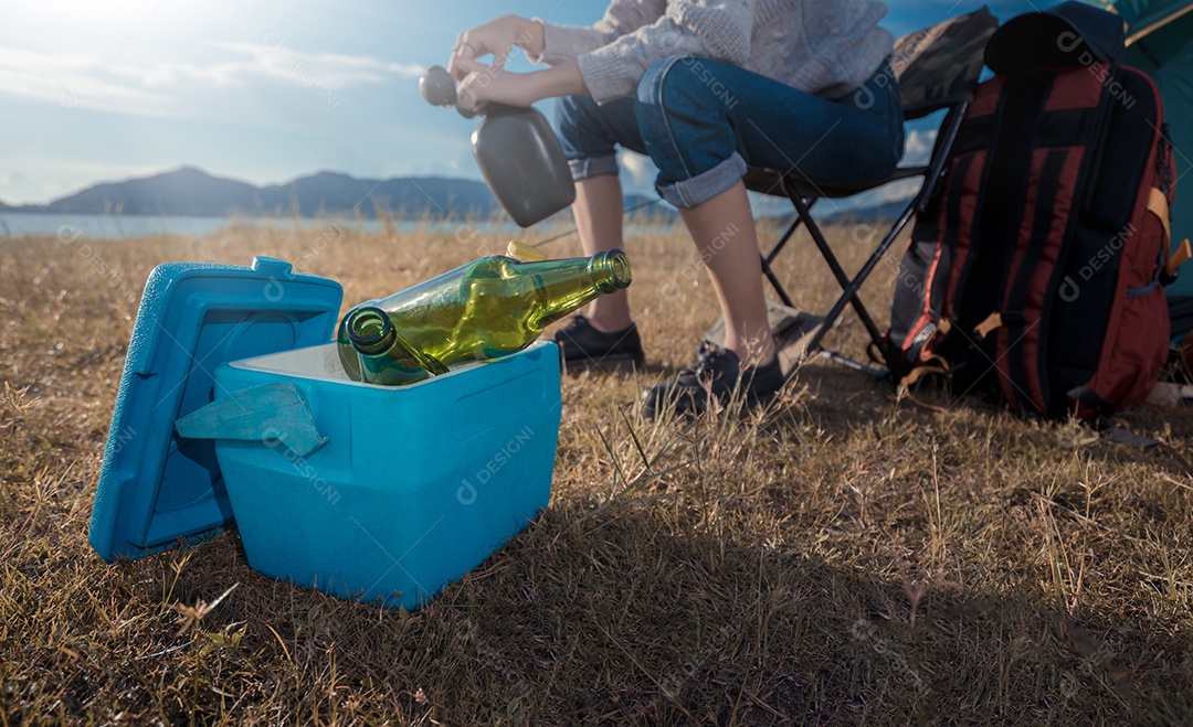 Mulher acampando sentada relaxa sozinha com bebidas