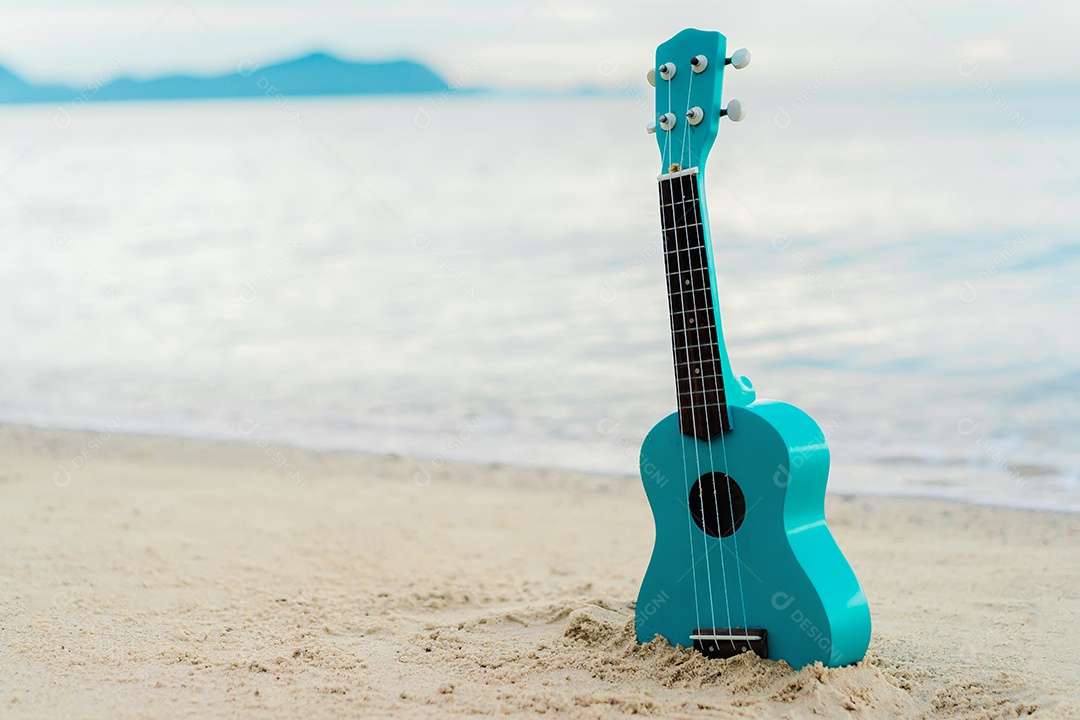 Ukulele azul enterrado na areia da praia