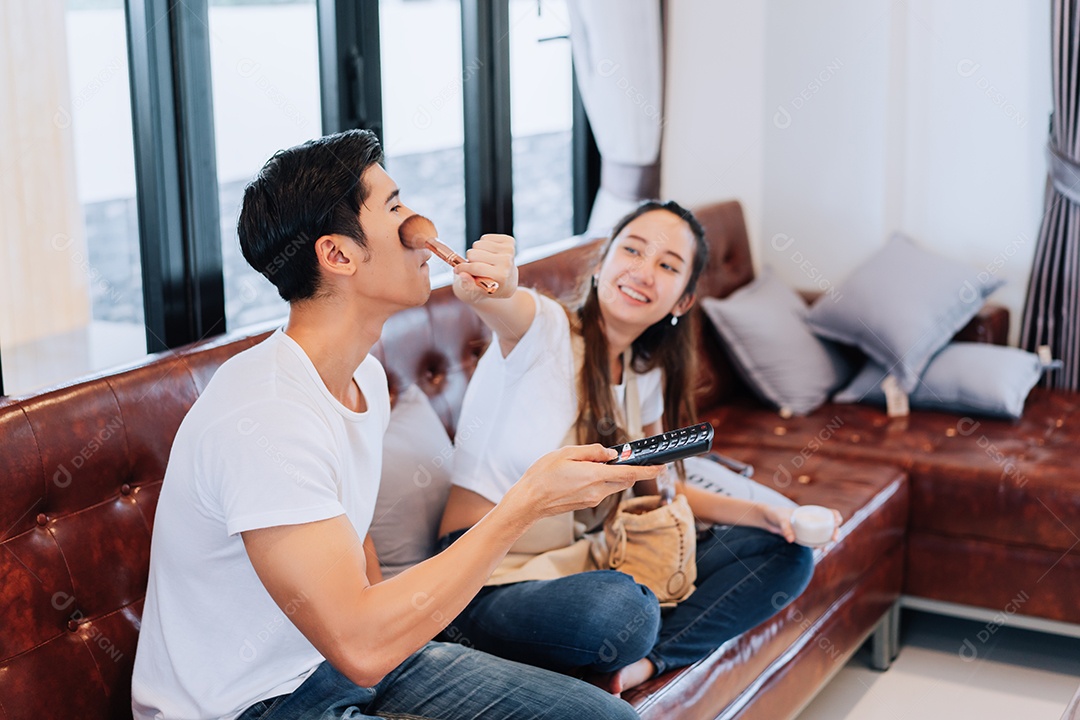 Casal feliz namorada engraçada maquiagem namorado assistindo programa de comédia na televisão