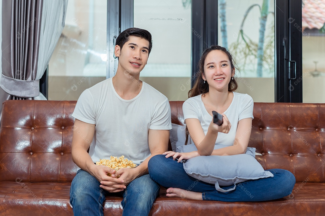 Jovem asiático e mulher casal juntos assistindo televisão