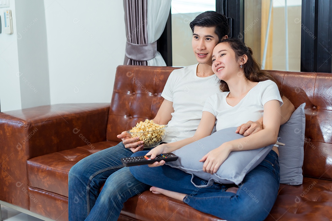 Jovem asiático e mulher casal juntos assistindo televisão