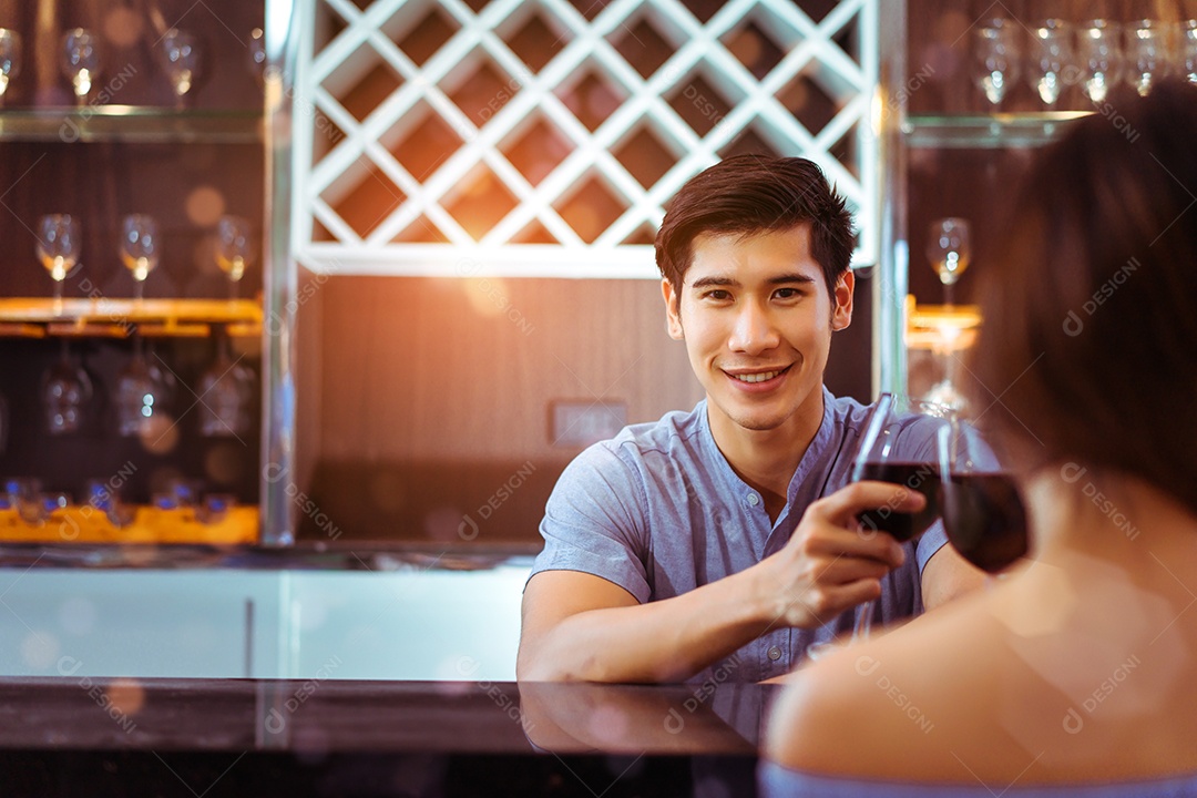 Jovem casal asiático juntos, homem e mulher, brindam taças de vinho