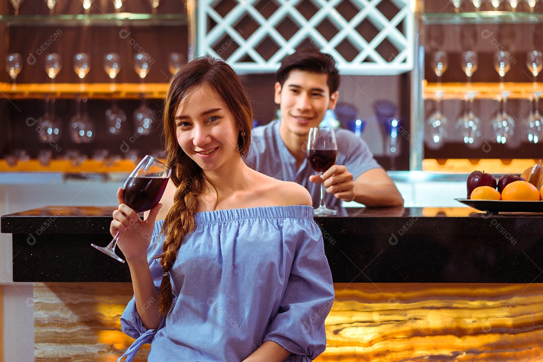 Jovem casal asiático juntos, homem e mulher brindam taças de vinho