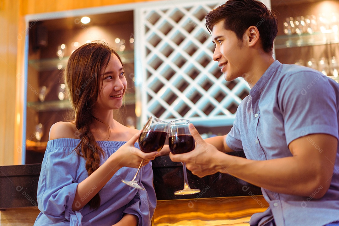 Jovem casal asiático juntos, homem e mulher brindam copos de vinho