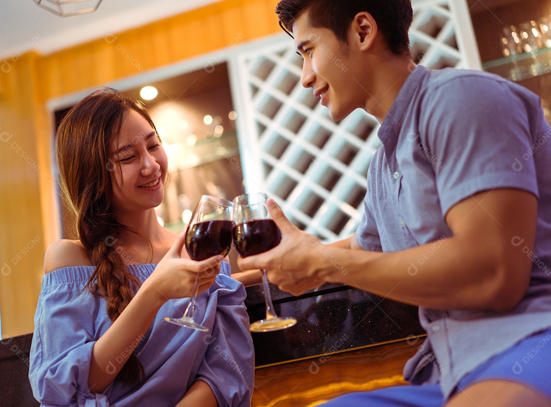 Jovem casal asiático juntos, homem e mulher brindam copos de vinho